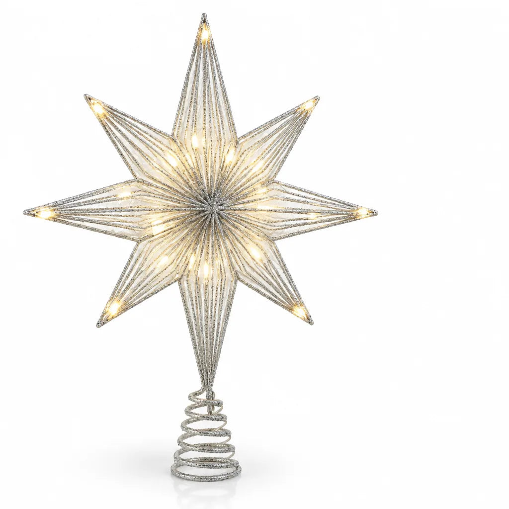 Silver glittered eight-point star Christmas tree topper with warm white LED lights glowing along its fabric panels, mounted on a coiled wire spring base against a white background.