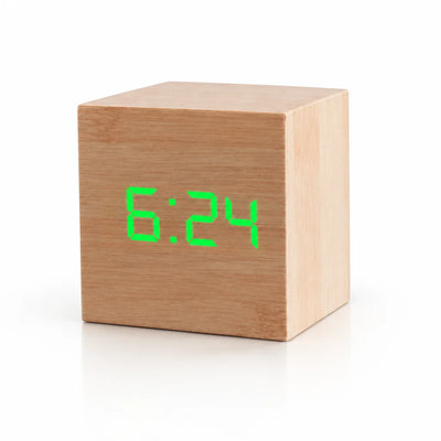 Cube-shaped digital LED alarm clock in light wood, showing the time 6:24 in bright green digits on a plain white background.