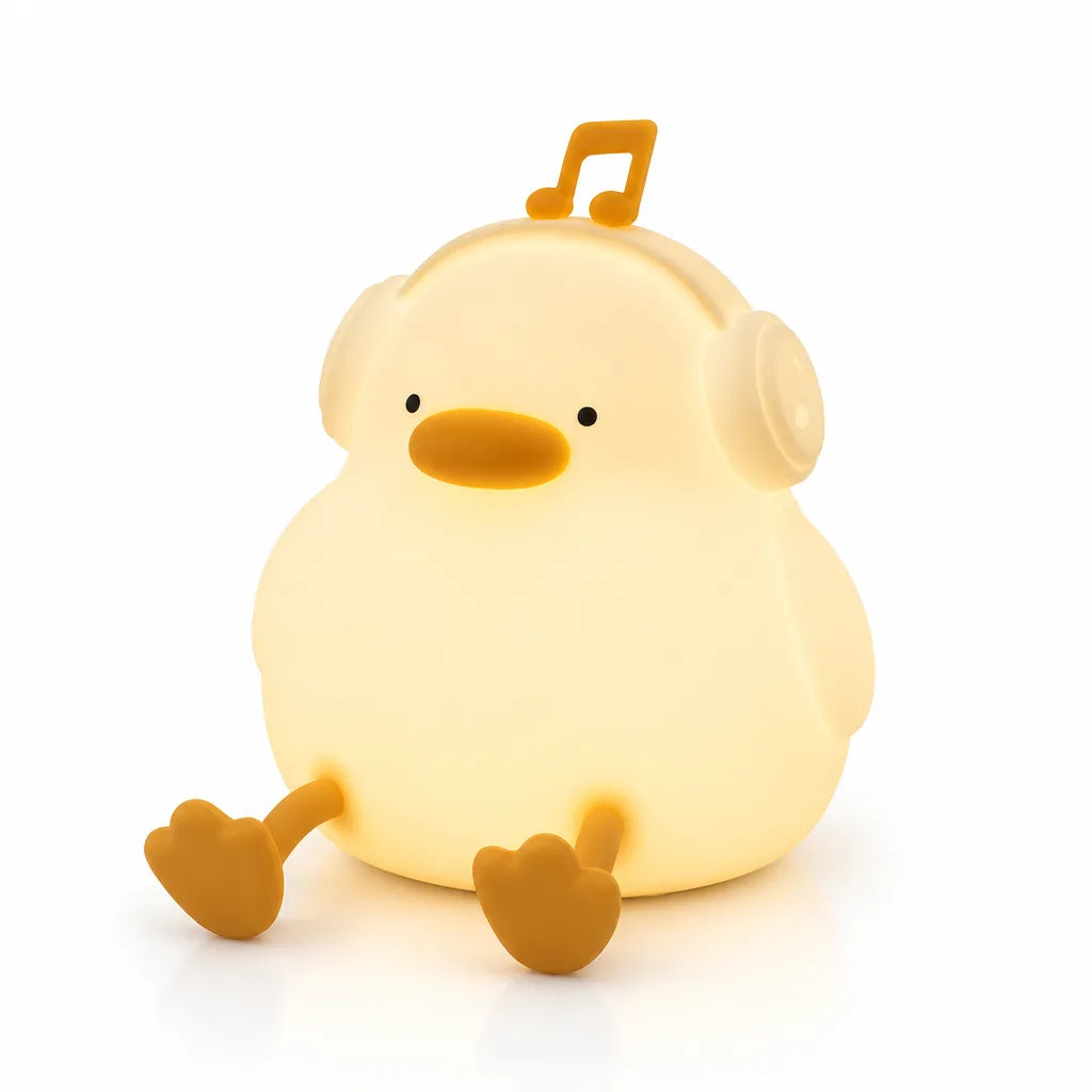 A glowing pale yellow Duck Night Light shaped like a round, chubby duckling sitting with its legs stretched out, wearing silicone headphones topped with a music note, lit up against a plain white background.