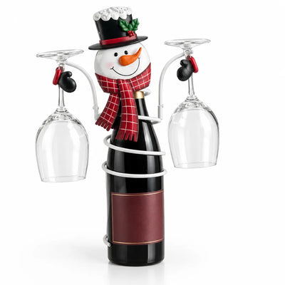 Snowman bottle holder in white metal, with a top hat, carrot nose and red plaid scarf, wrapped around a dark wine bottle while its mitten-tipped arms hold two upside-down wine glasses.