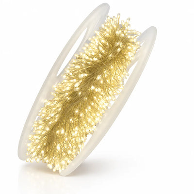 A coil of LED copper wire string lights wound densely onto a translucent plastic reel, all of the tiny bulbs lit in a warm golden glow against a white background.