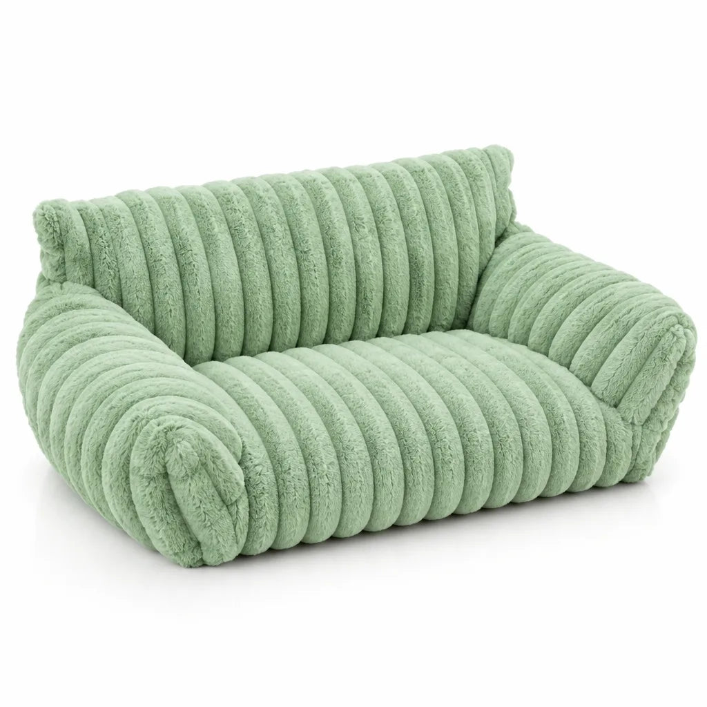 Sage green plush pet bed shaped like a small two-seater sofa, with thick ribbed faux-fur channels across the backrest, seat and rolled arms, shown alone against a plain white background.