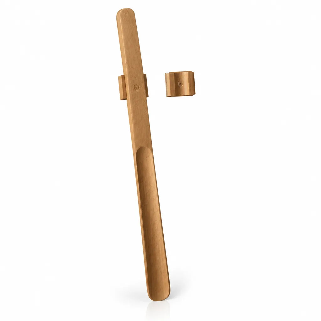 Extra-long natural walnut wood shoehorn with a scooped handle, shown upright beside its separate curved magnetic wall mount against a white background.