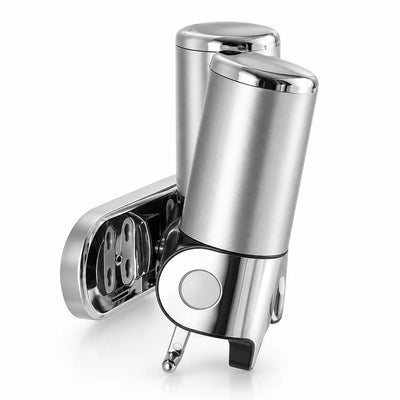 Silver stainless steel wall-mounted soap dispenser shown at an angle against a white background, with its chrome push button and spout at the front and the open mounting bracket visible behind the cylindrical body.