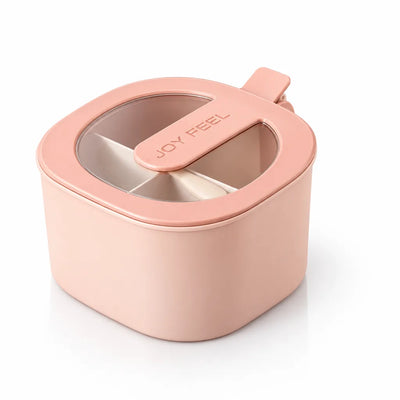 A pale pink Joy Feel spice storage jar with a clear window lid, a built-in matching spoon that slots across the top, and a divided interior with cream-colored compartments visible through the window.