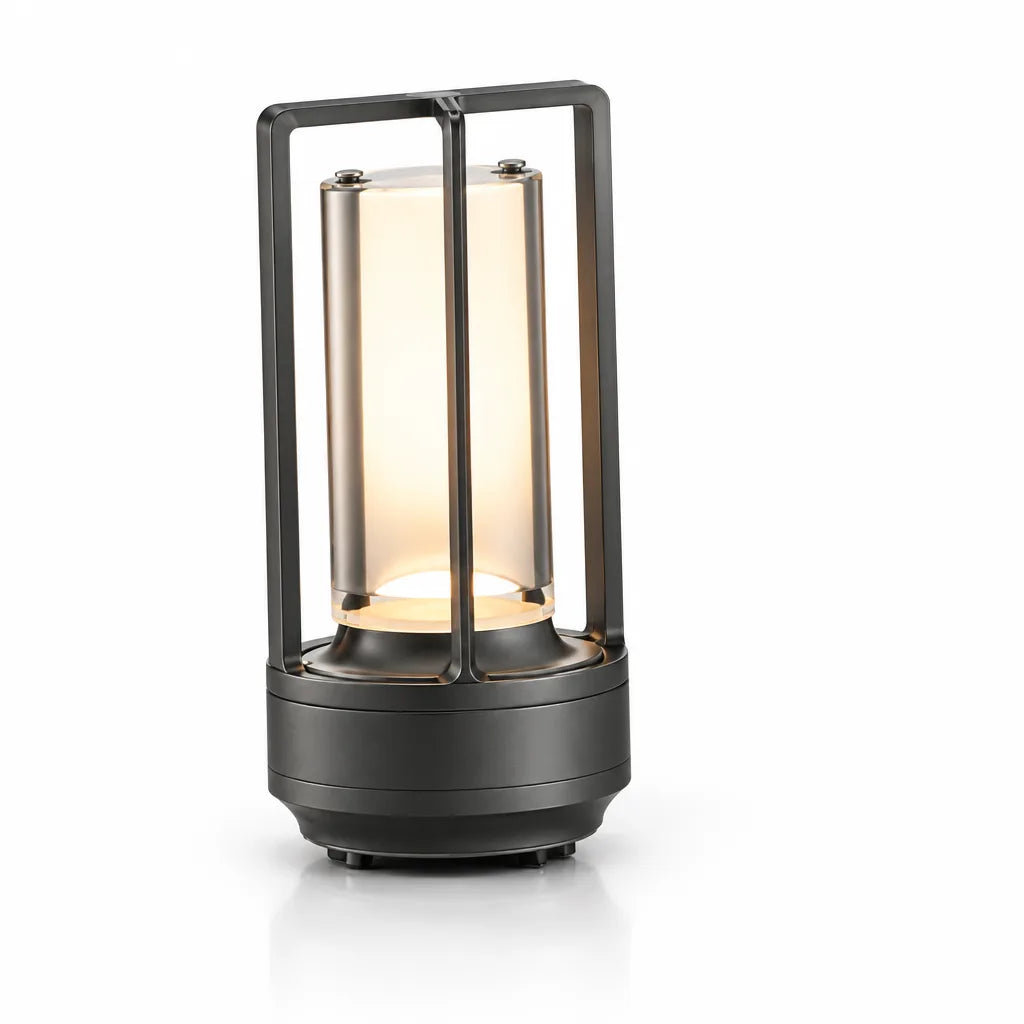 Cordless table lamp with a matte black metal frame and cylindrical frosted glass shade glowing warm amber, shown lit on a plain white background.