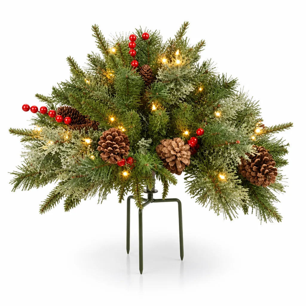 Lit Christmas arrangement with pine cones and berries on a tripod stake, shown as a single fan-shaped spray of mixed green and frosted fir branches dotted with warm white lights, brown pine cones and red berry clusters, mounted on a dark green three-pronged ground spike against a white background.